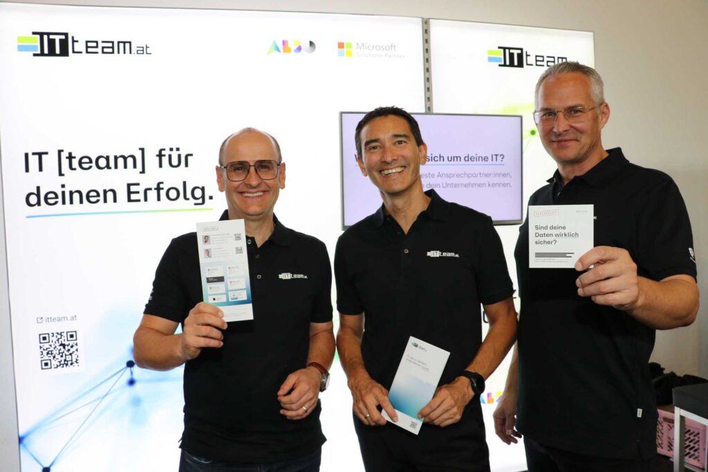 IT-Team-Mitarbeiter mit Infomaterial vor der IT-Team-Wand
